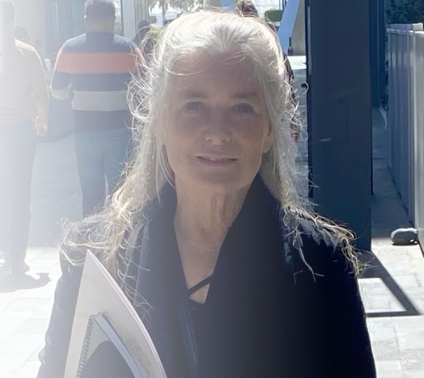Woman with long gray hair holding folder outdoors