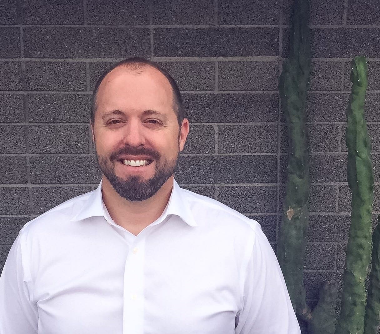 Smiling man in white shirt against brick wall