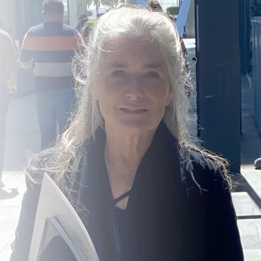 Woman with long gray hair holding folder outdoors